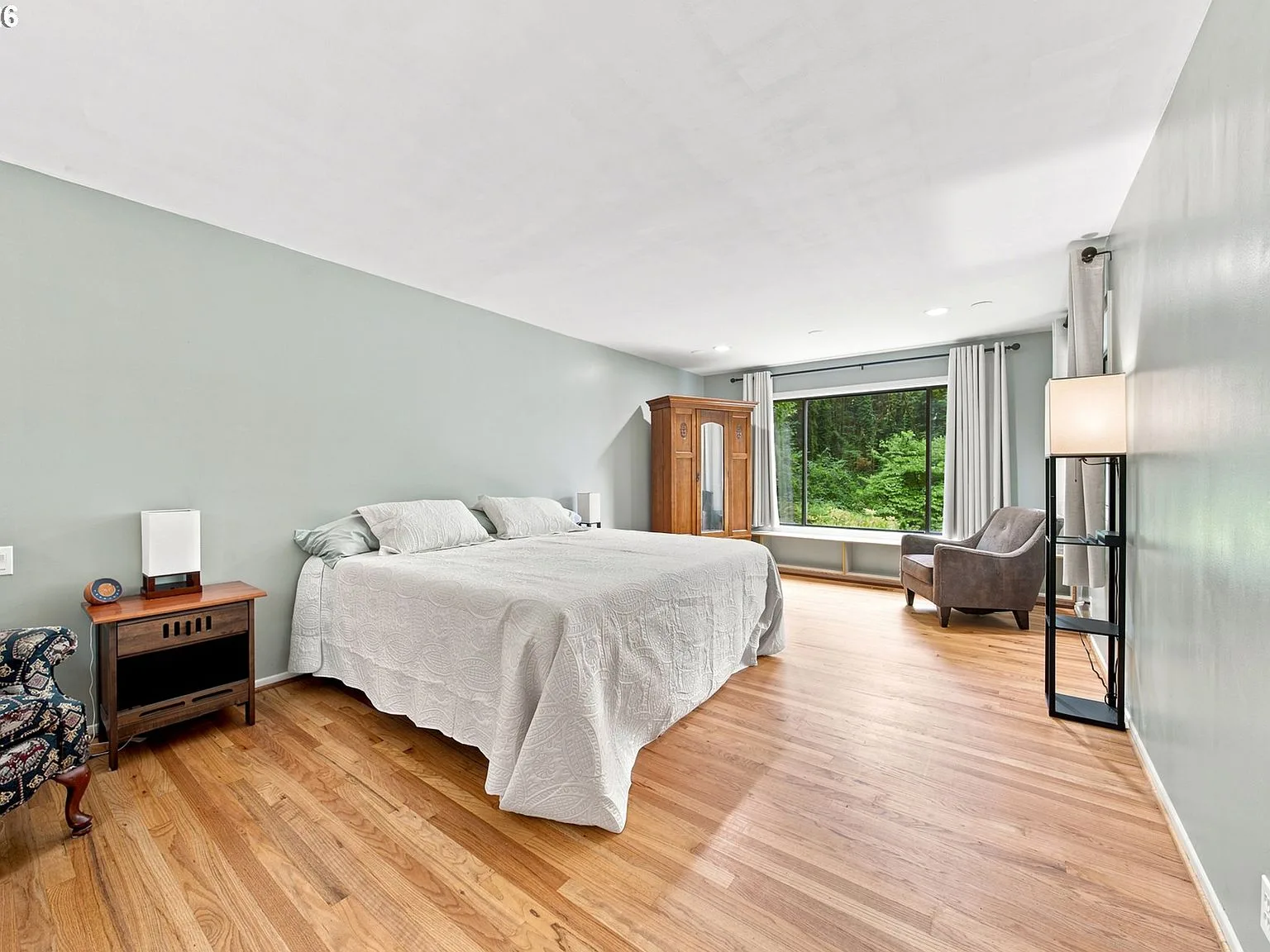 Primary bedroom with large window overlooking treetop forest views