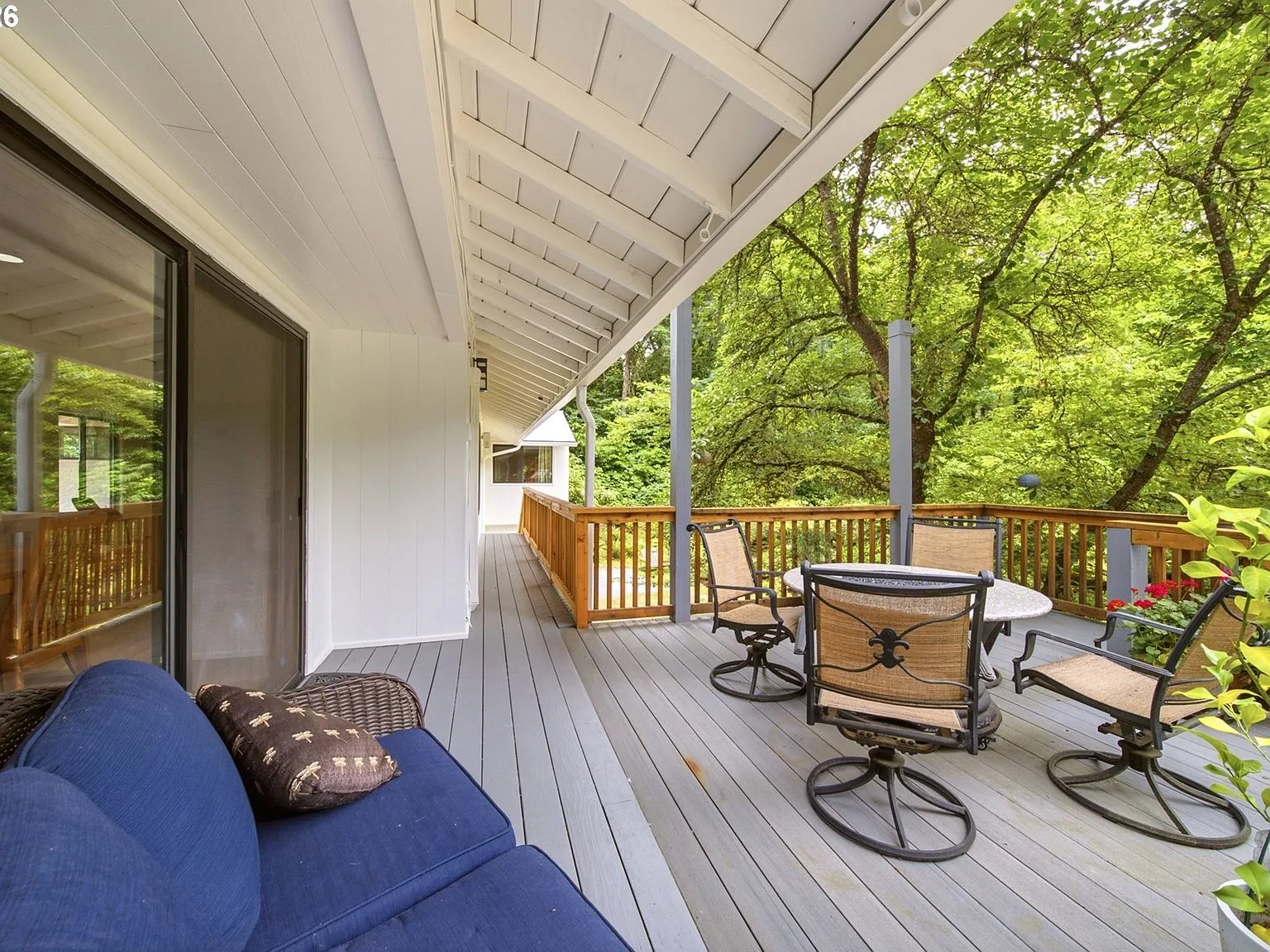 Covered back deck surrounded by mature forest trees