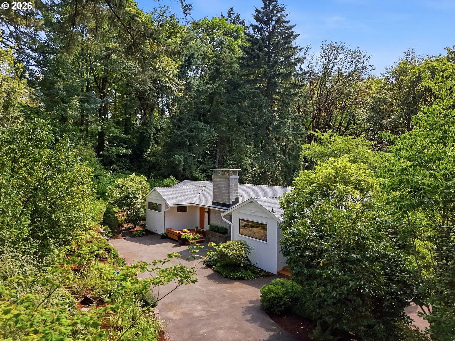 Aerial view of 1111 SW Coronado St showing the mid-century residence nestled among nearly 3 acres of mature evergreen forest