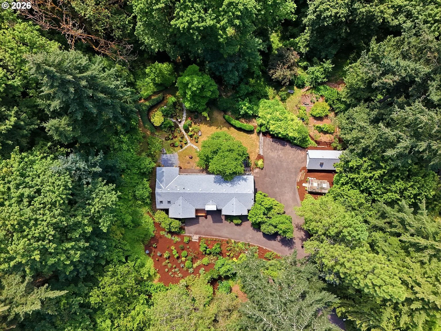 Overhead aerial showing the nearly 3-acre property lot among dense evergreen forest