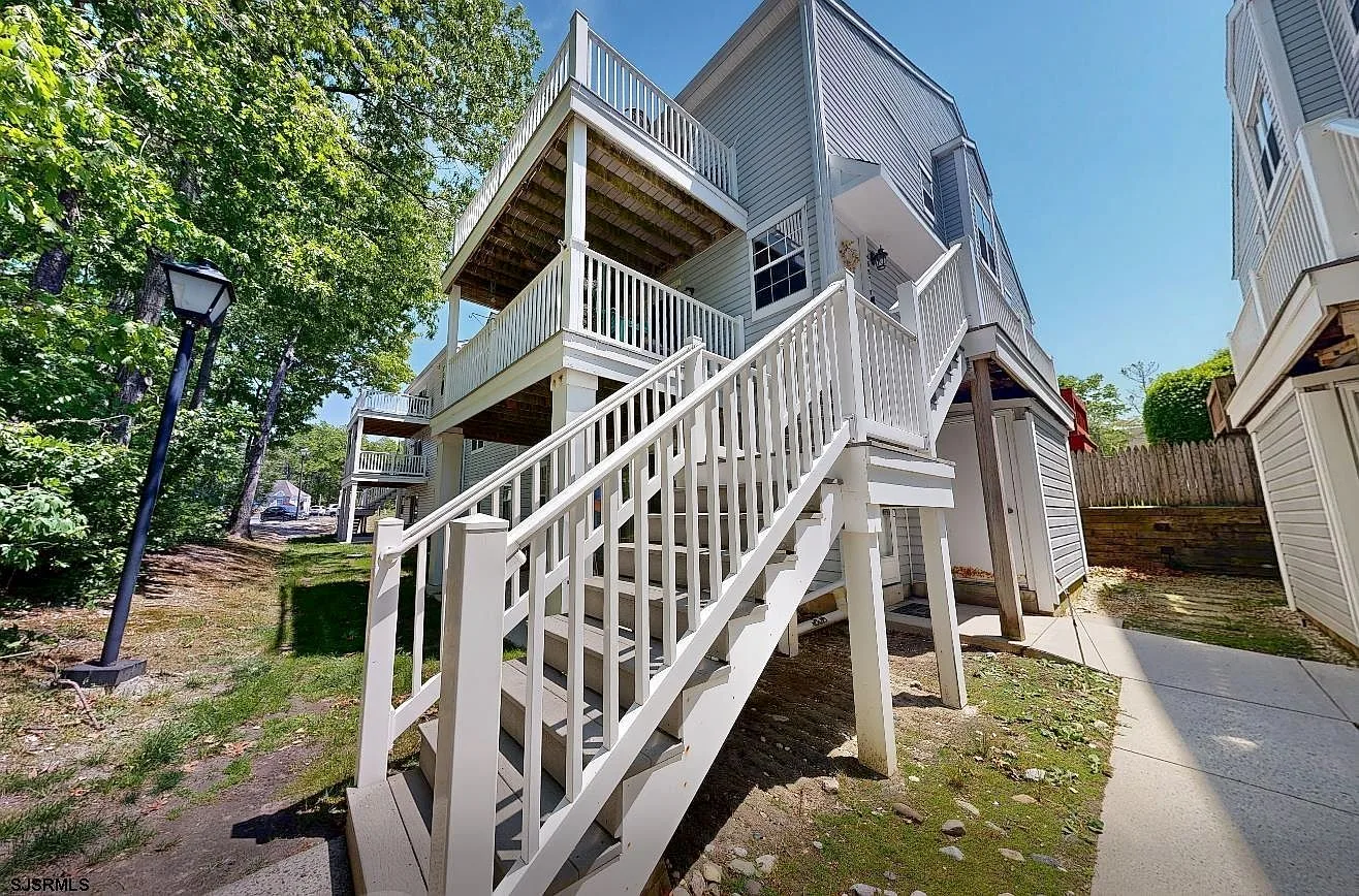Exterior view of 4885 Bayberry Place, a grey-sided condominium with exterior staircase in Mays Landing NJ