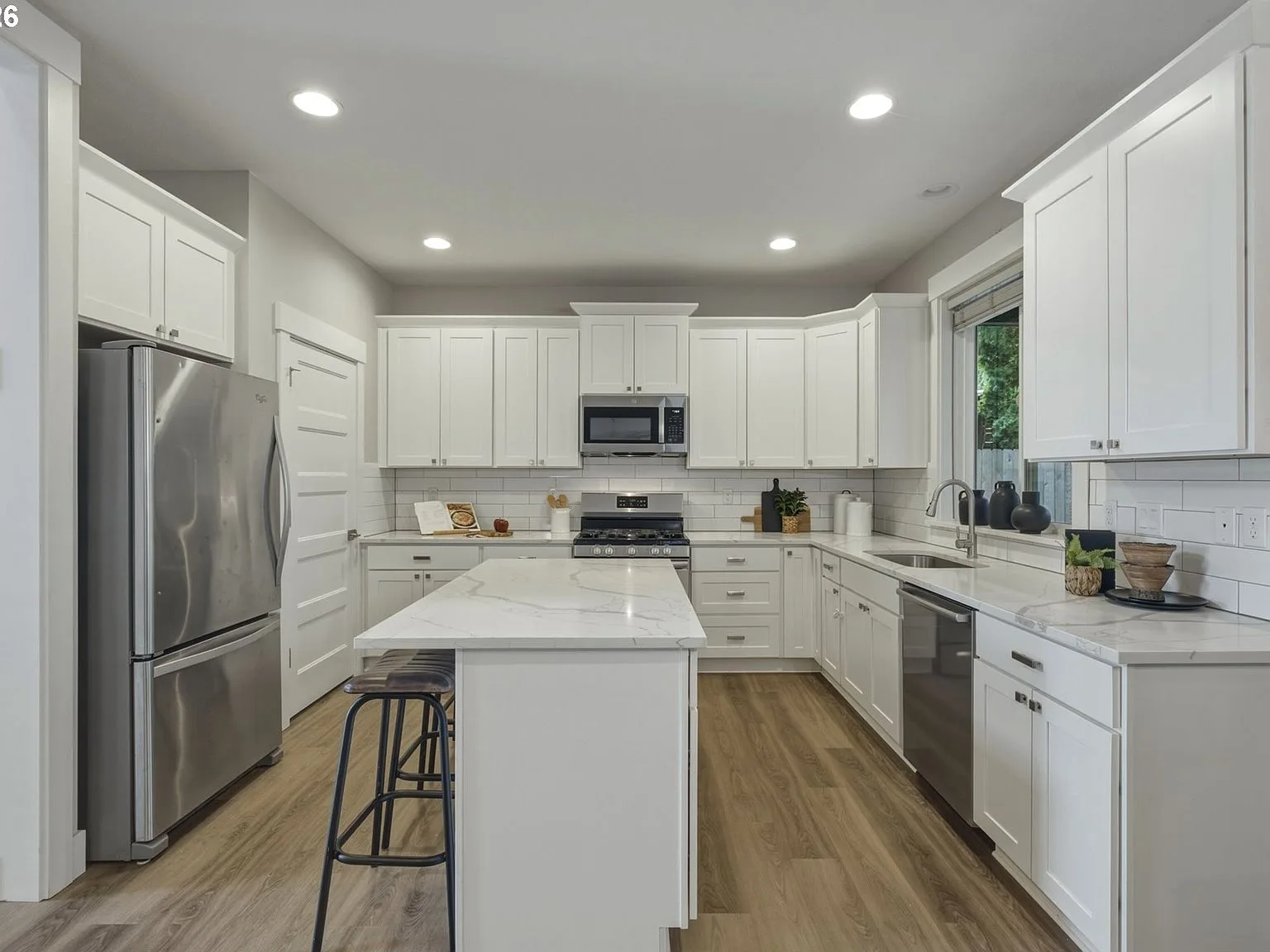 Modern kitchen with white cabinetry, quartz island, and stainless steel appliances