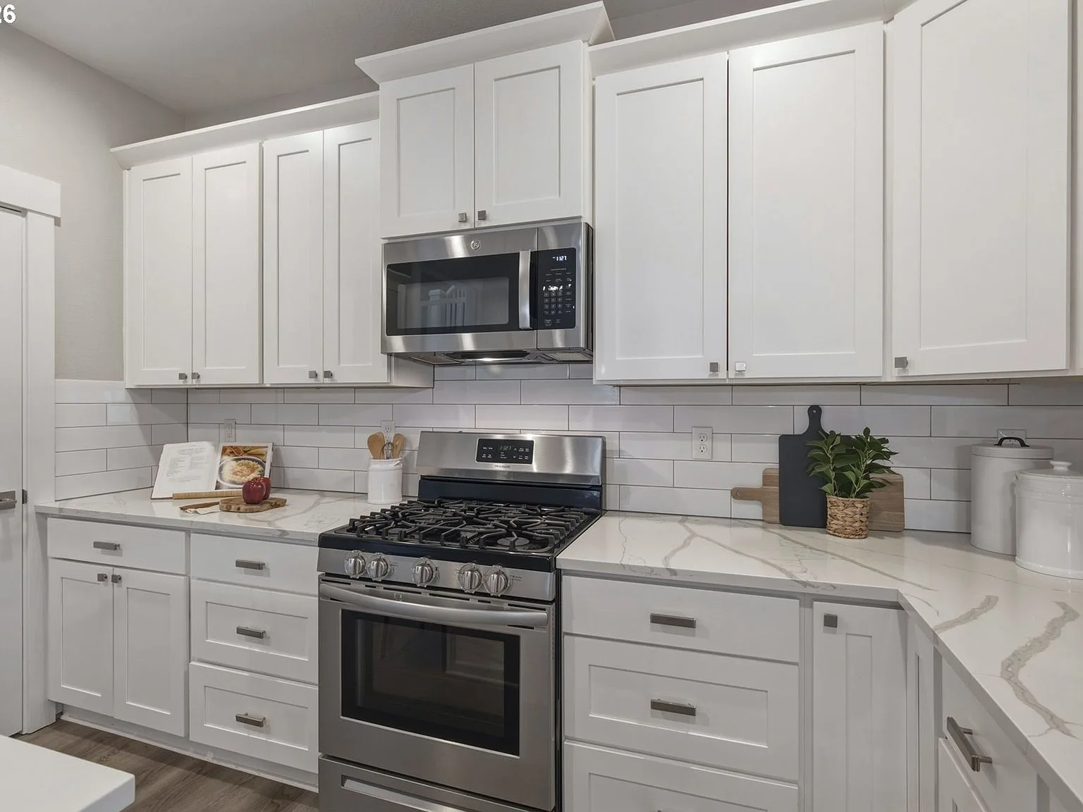 Kitchen focus shot showing white shaker cabinets, gas range, and subway tile backsplash