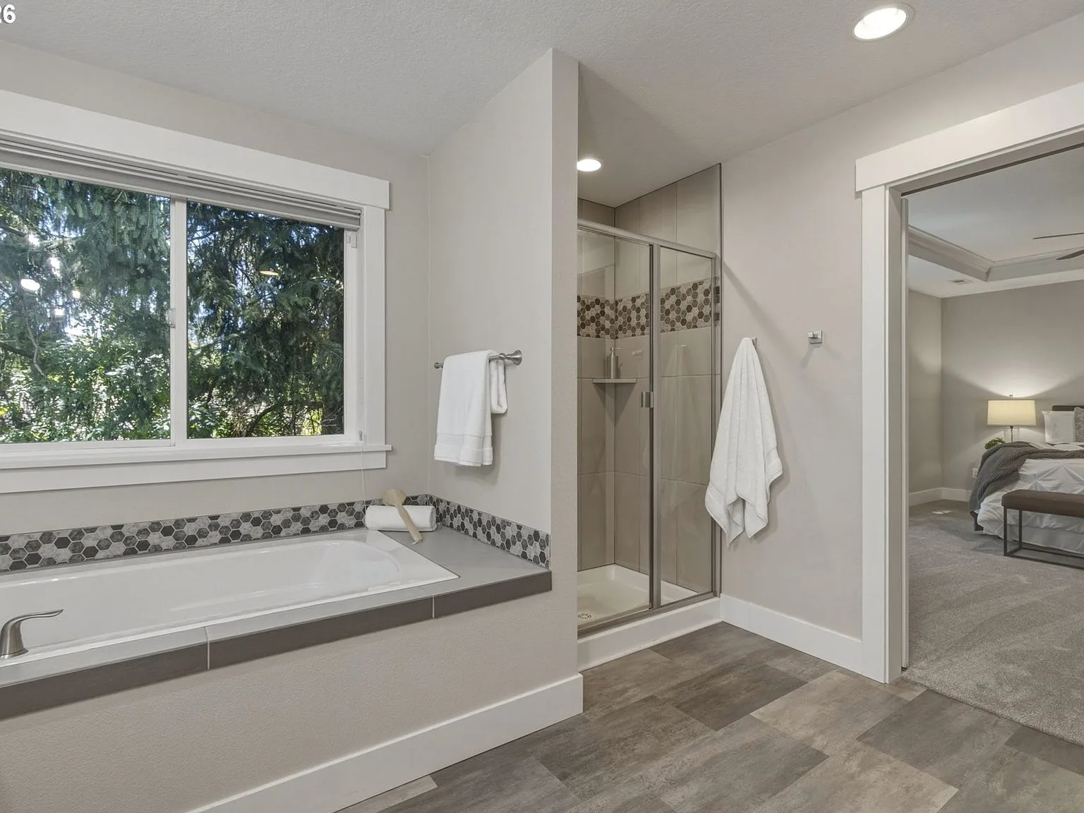 Primary bathroom soaking tub with tile surround and natural daylight