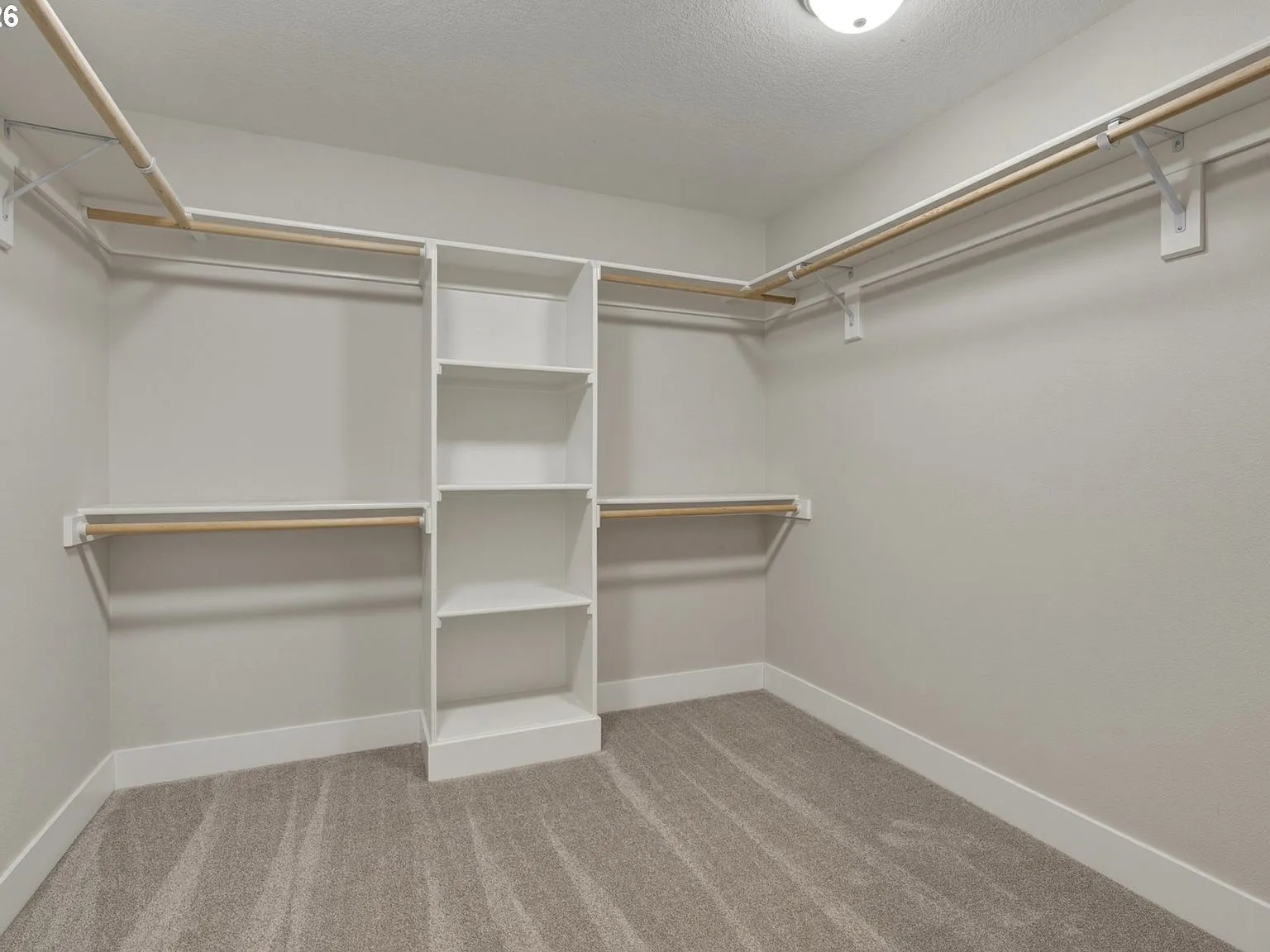 Walk-in closet with white built-in shelving and wood rods