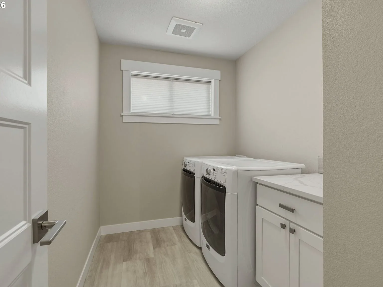 Laundry room with LVP flooring, white cabinet, and quartz countertop