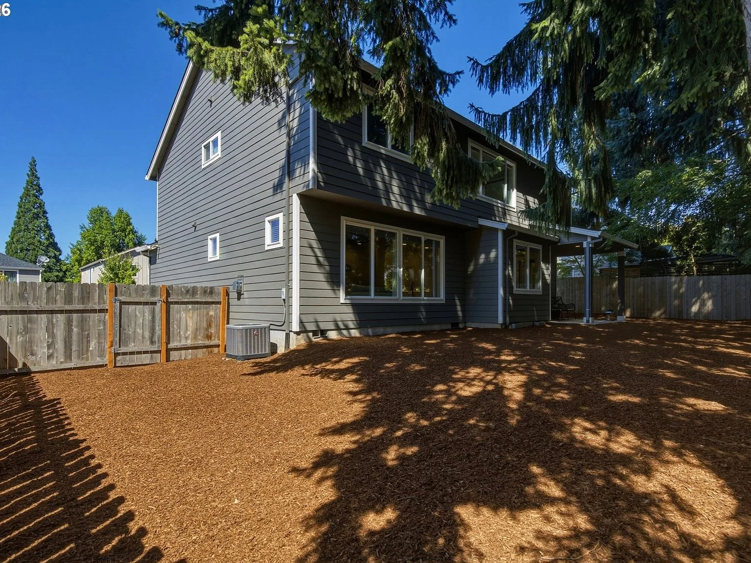 Rear exterior showing dark-grey siding, wood fence, and lawn