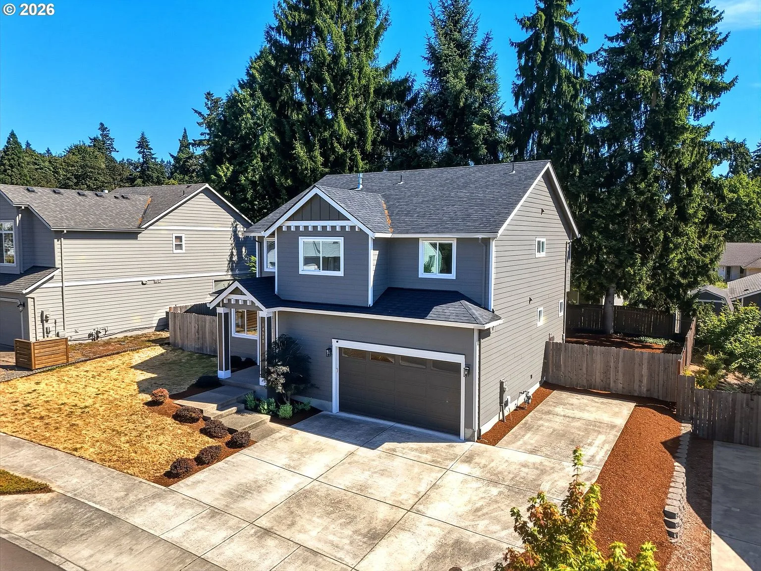 Elevated view of the two-story home showing grey lap siding and gabled roofline