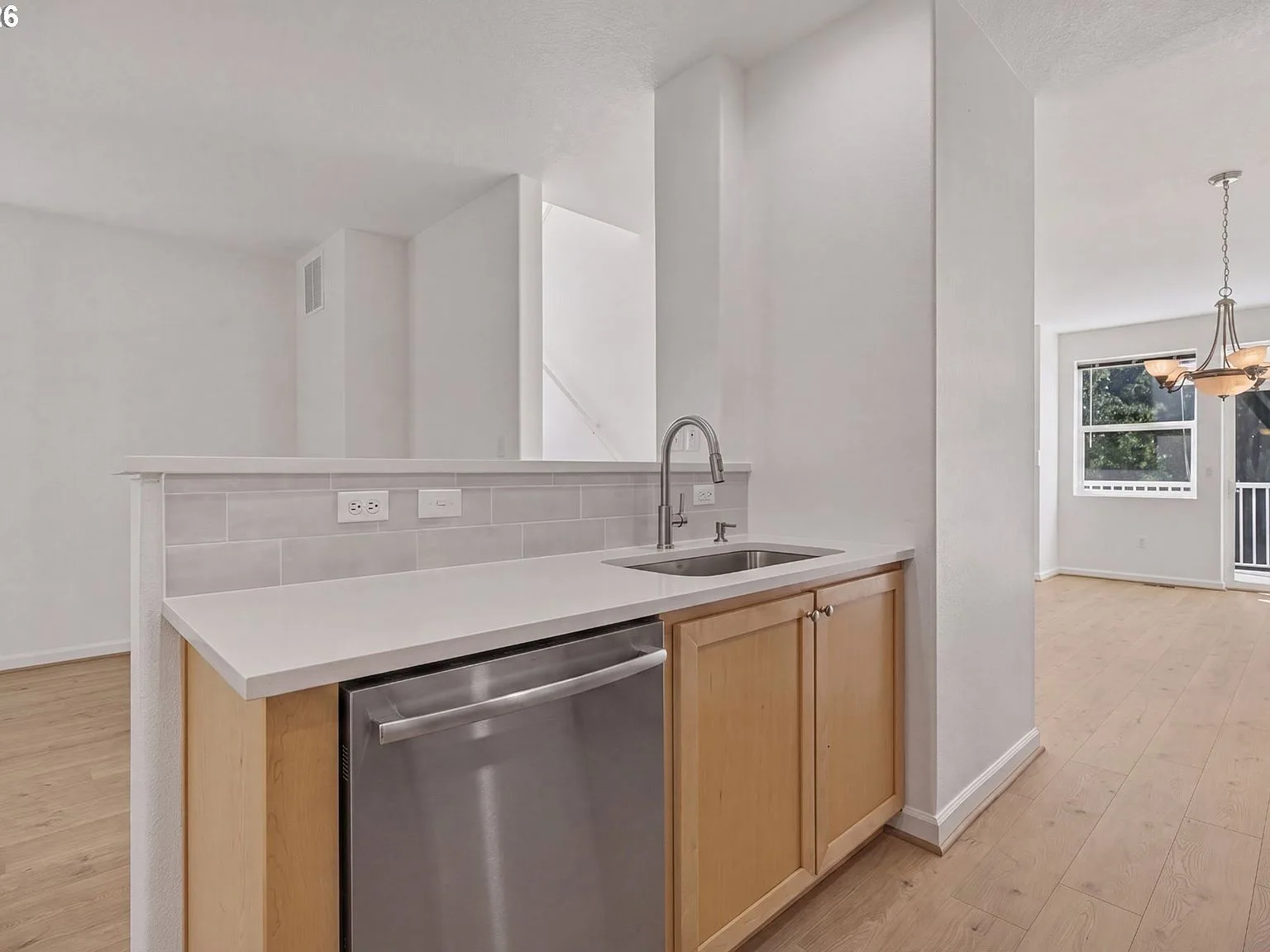 Kitchen sink area with quartz countertops and tile backsplash