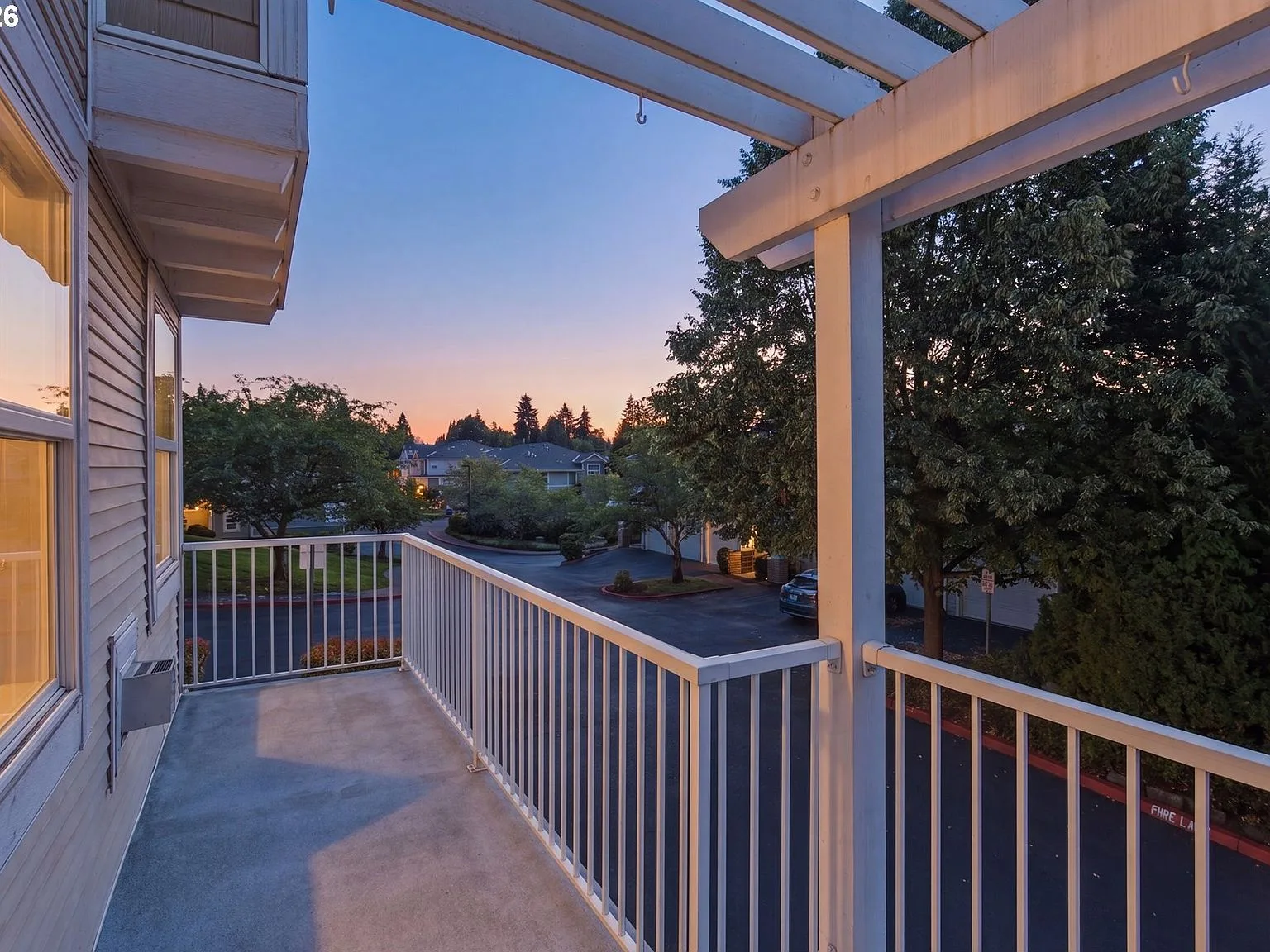 Spacious front balcony with white pergola at sunset