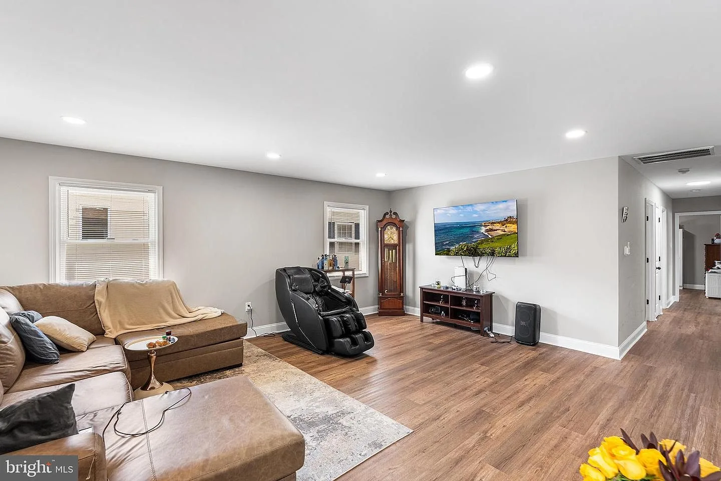 Bright living room with light grey walls, recessed lighting, and wood-look flooring