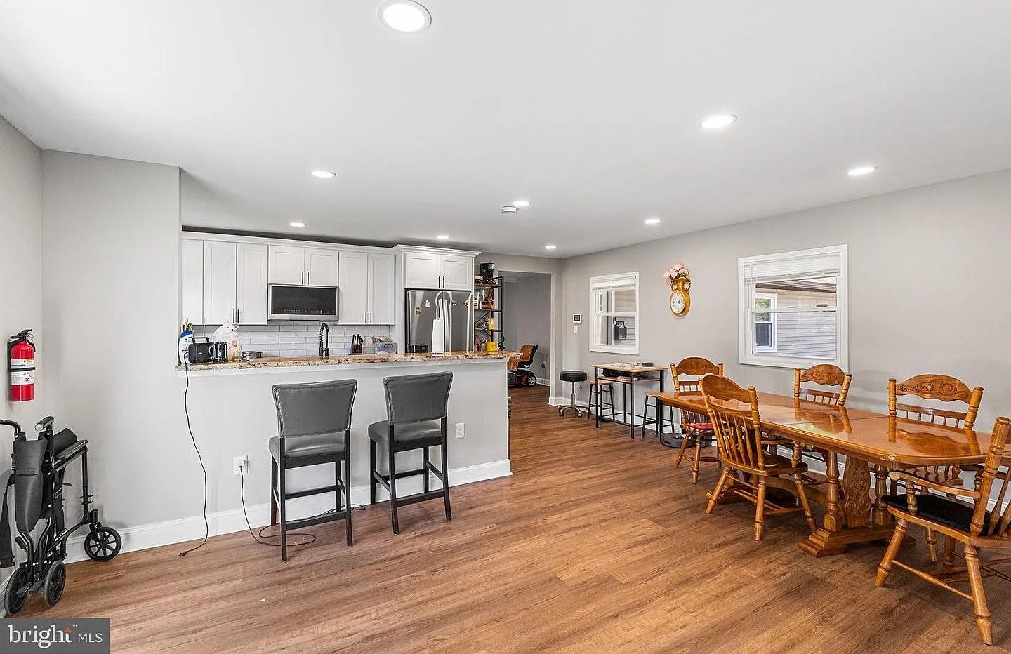 Open-concept kitchen and dining area with white cabinetry, granite countertops, and wood-look flooring