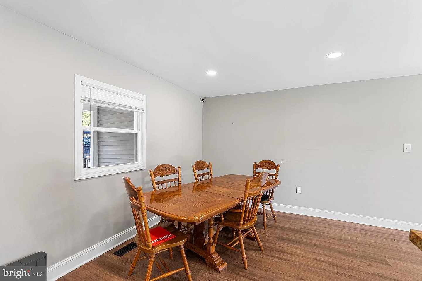 Dining room with light grey walls, recessed lighting, and window with white blinds