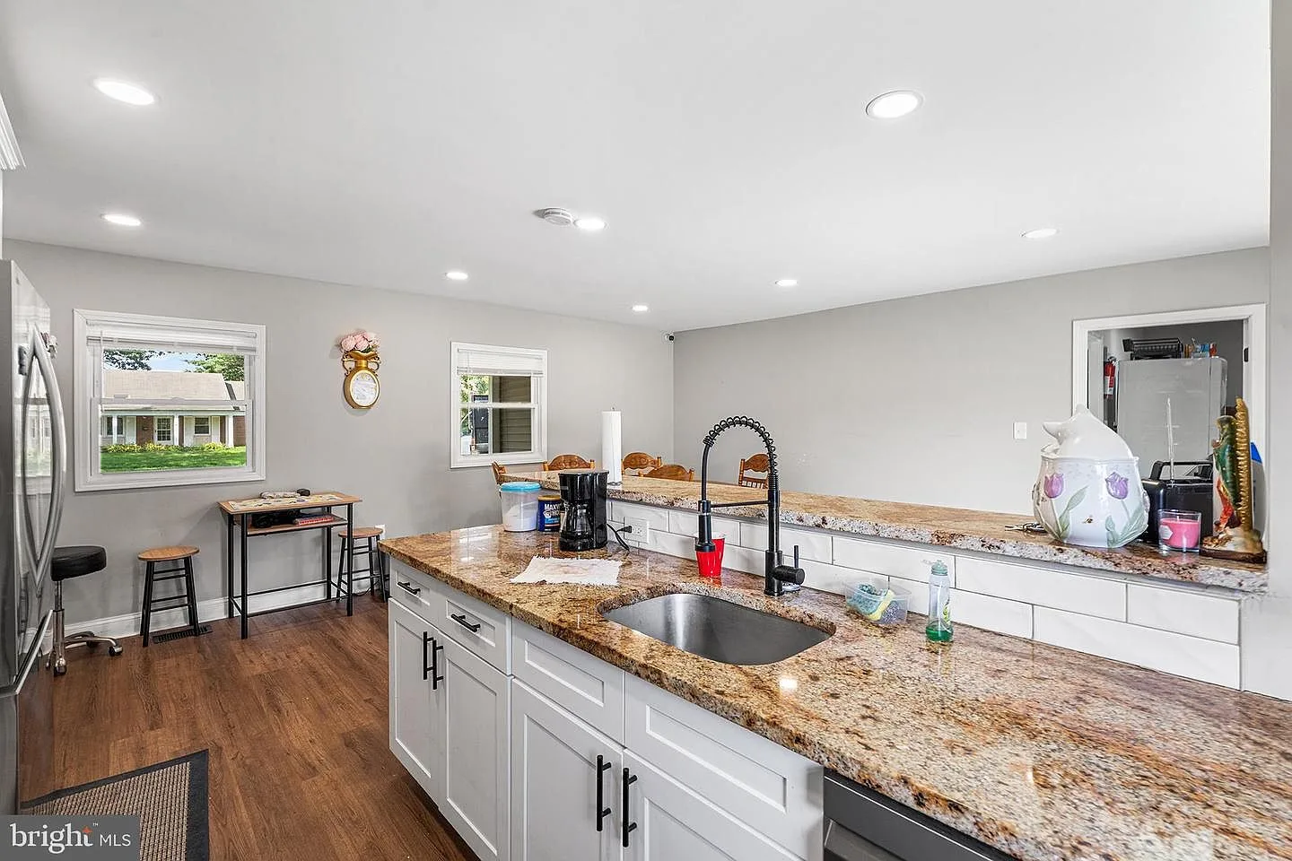 Renovated kitchen with white shaker cabinets, granite island, and subway tile backsplash