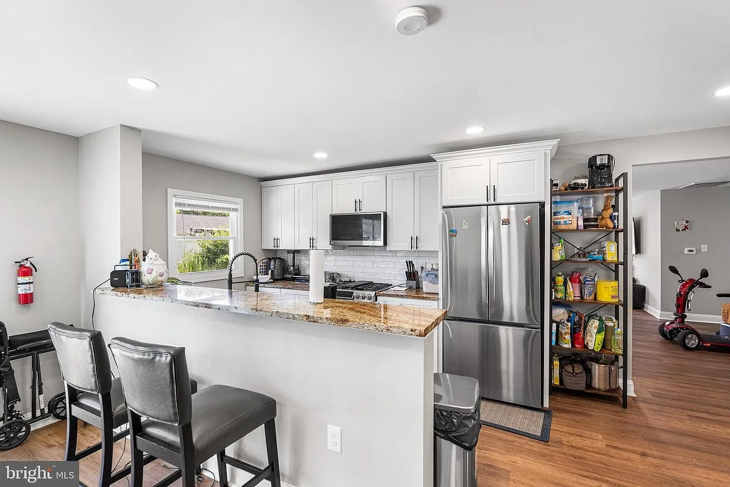 Kitchen breakfast bar with white cabinets, granite countertops, and recessed lighting