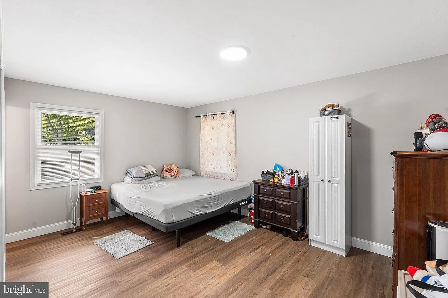 Secondary bedroom with grey paint, wood-look flooring, and natural daylight