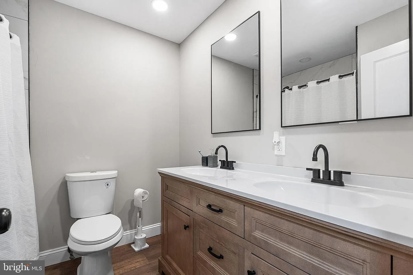 Modern double-vanity bathroom with light wood vanity, white countertop, and matte black fixtures