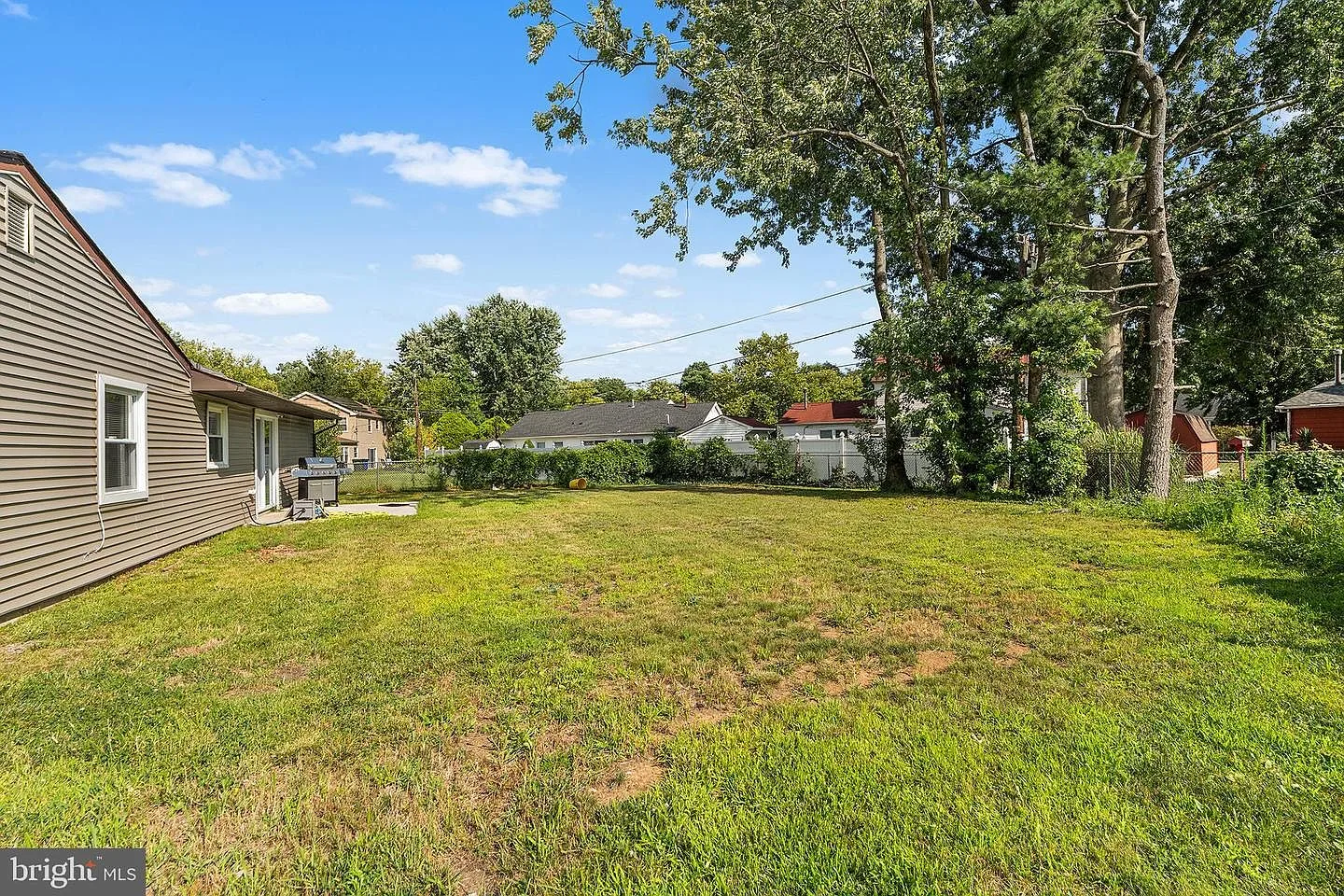 Grassy backyard lawn with horizontal siding on the ranch-style home