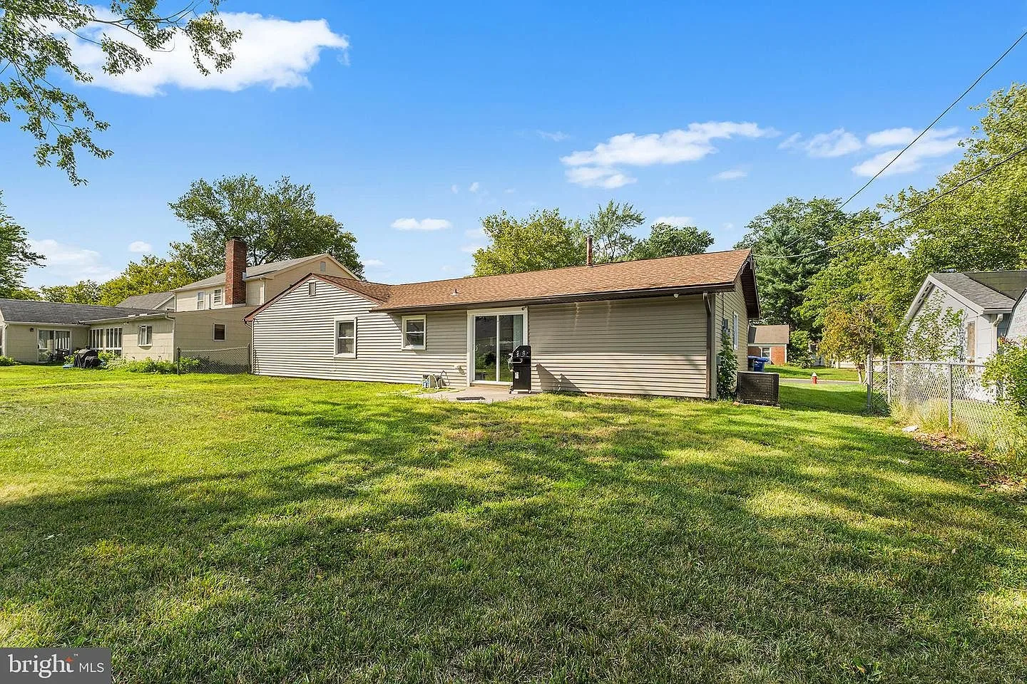 Backyard exterior with grassy yard, sliding glass door, and patio area