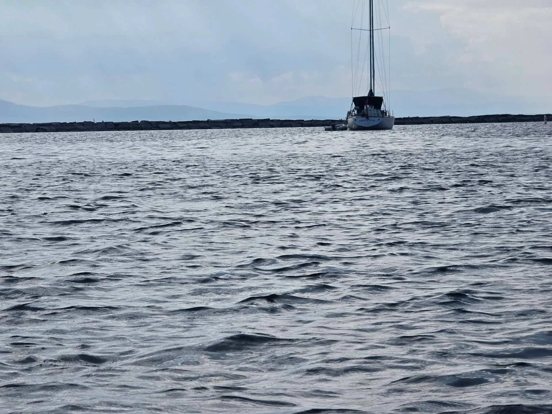 A sailboat glides across Lake Champlain with the Adirondack Mountains in the distance