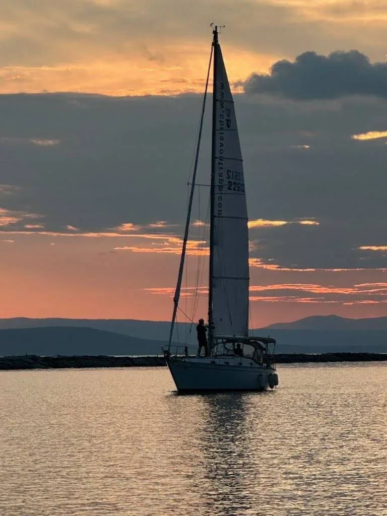 A sailboat silhouette against the golden sunset over Lake Champlain