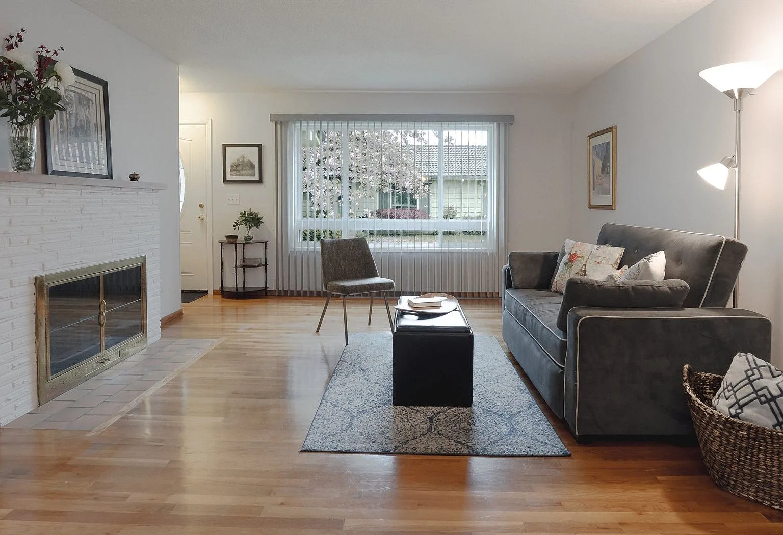Living room with white painted brick fireplace and hardwood floors