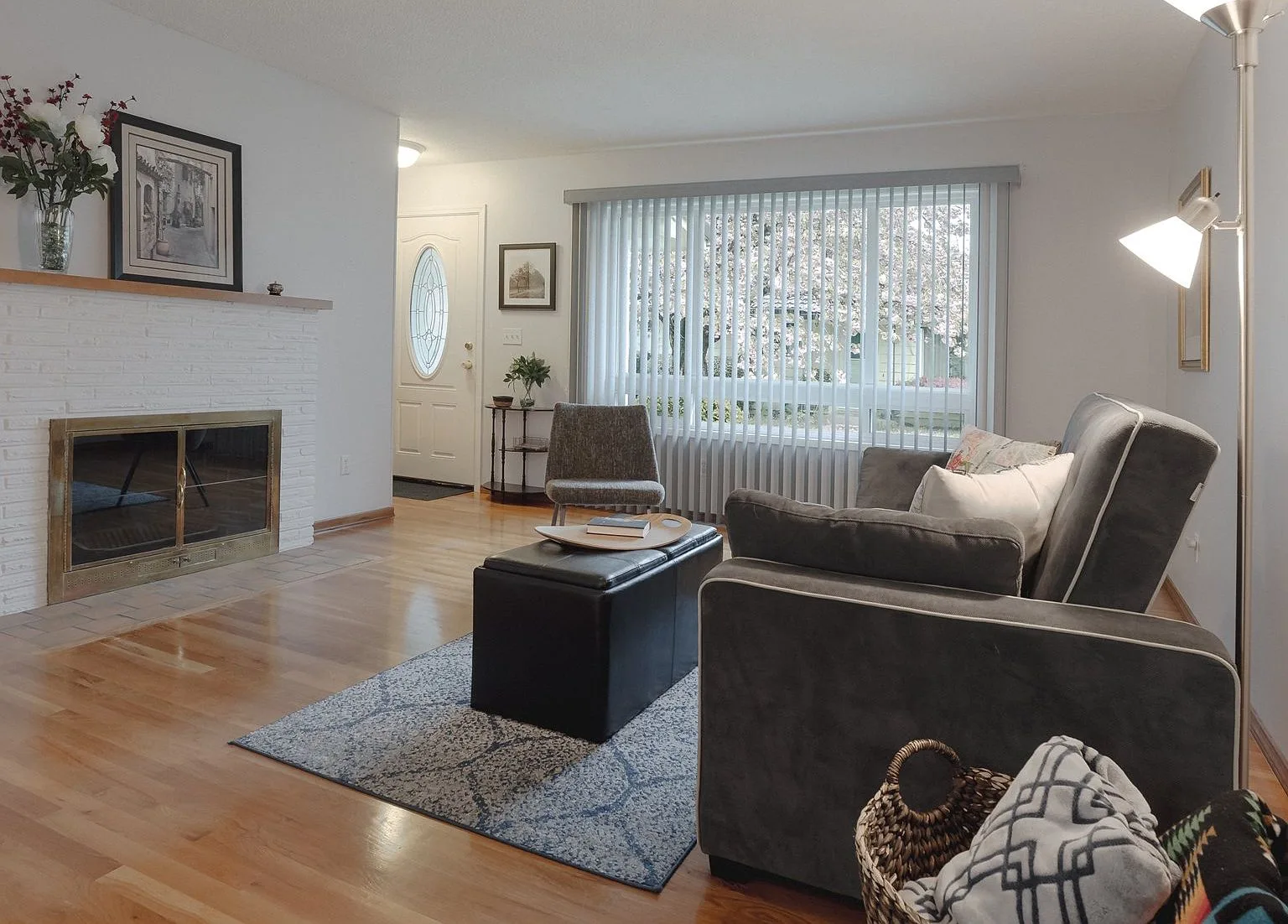 Living room with white painted brick fireplace and hardwood floors