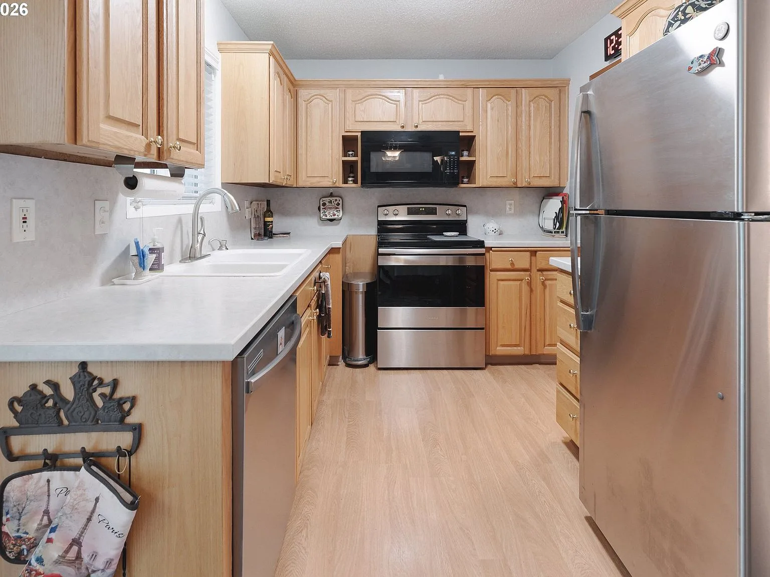 Galley kitchen with natural wood cabinets and stainless steel appliances