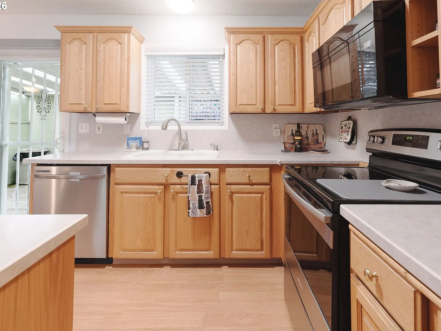 Galley kitchen with light oak cabinets and stainless steel appliances