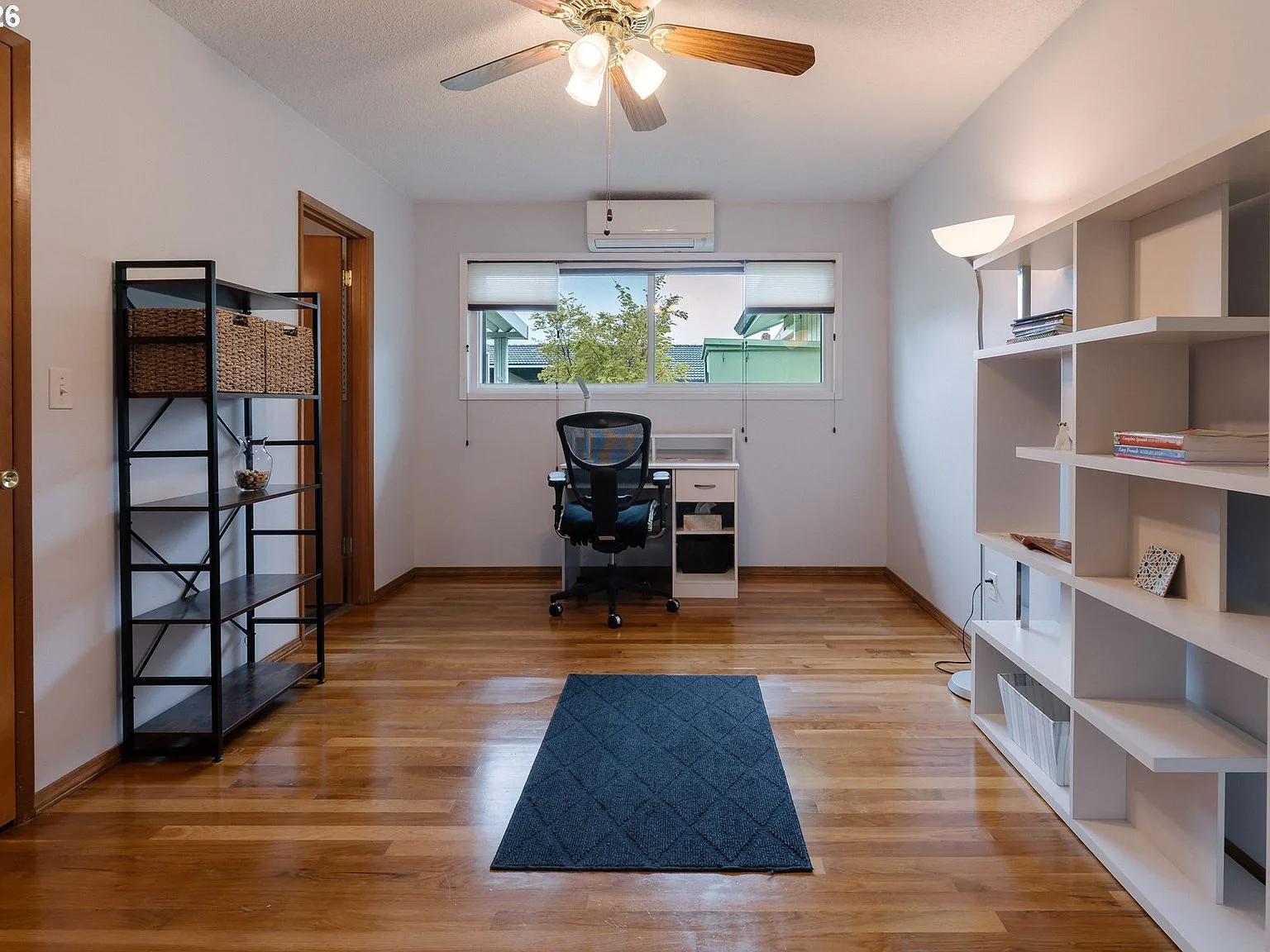 Bedroom set up as a home office with hardwood floors and ceiling fan