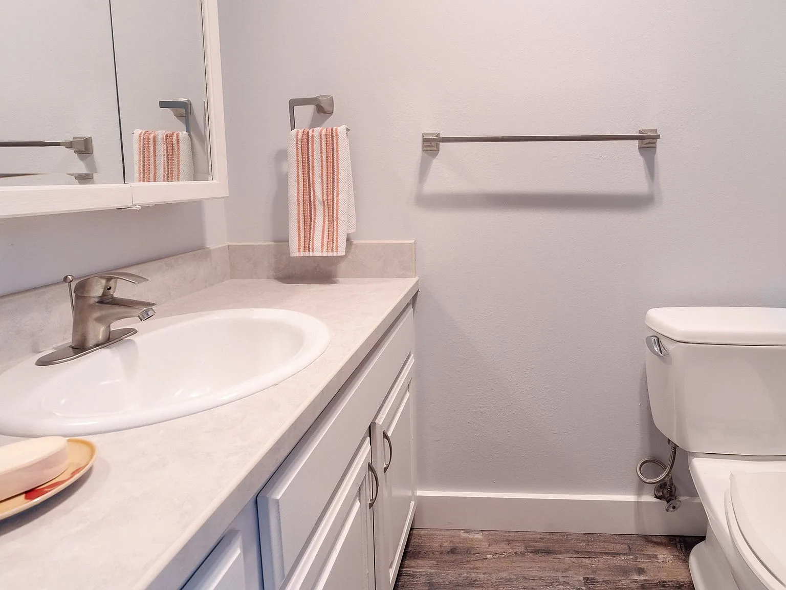Updated half bathroom with white vanity and wood-look flooring