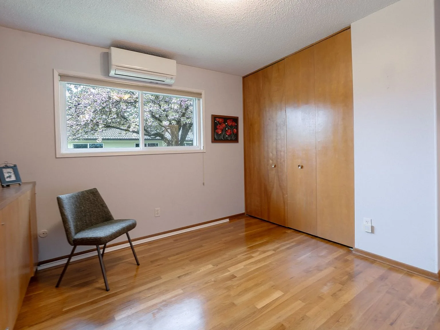 Bedroom with built-in wood-paneled closet doors and window onto trees
