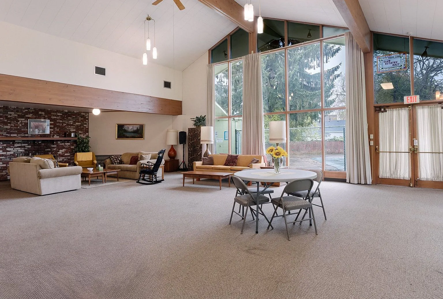 Community clubhouse with vaulted wood-beam ceiling and brick fireplace wall