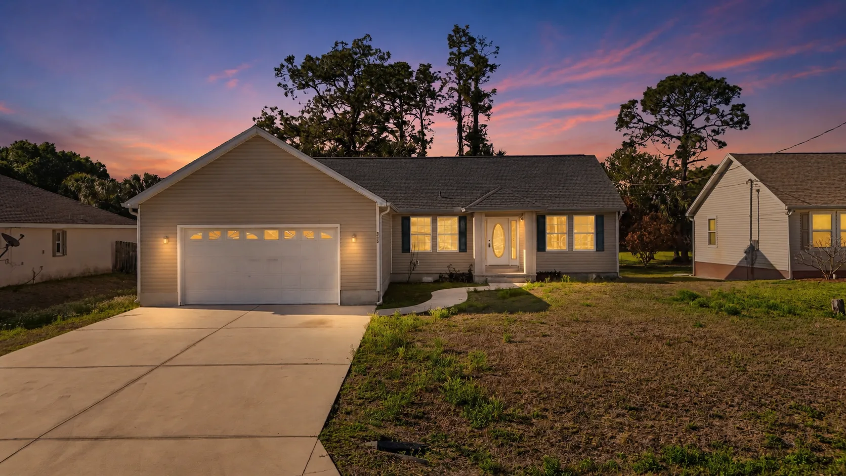 3005 14th St W exterior at dusk — single-story ranch home with warm interior and porch lights
