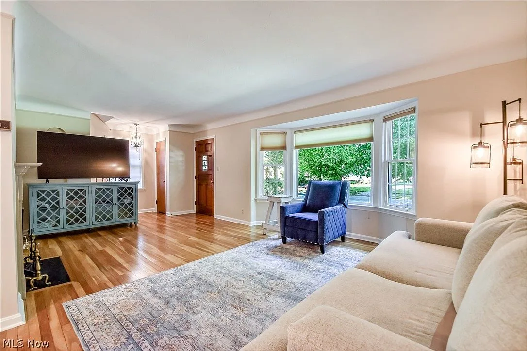 Spacious living room with hardwood floors, natural light, and classic Colonial character