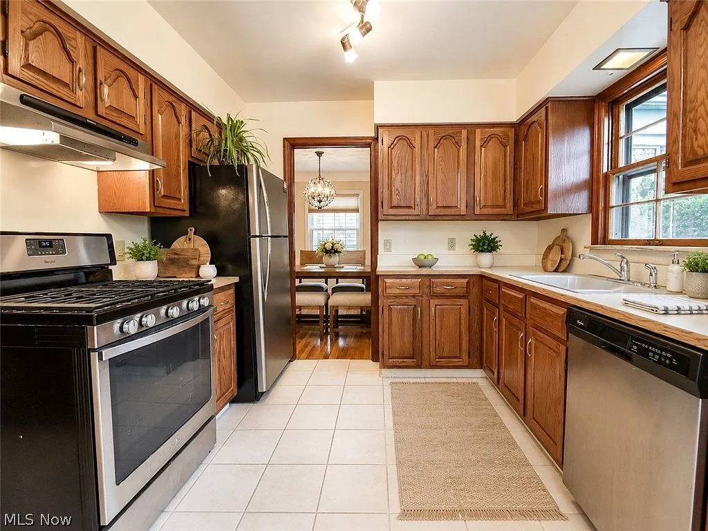 Kitchen with oak cabinetry, stainless steel appliances, and tile flooring