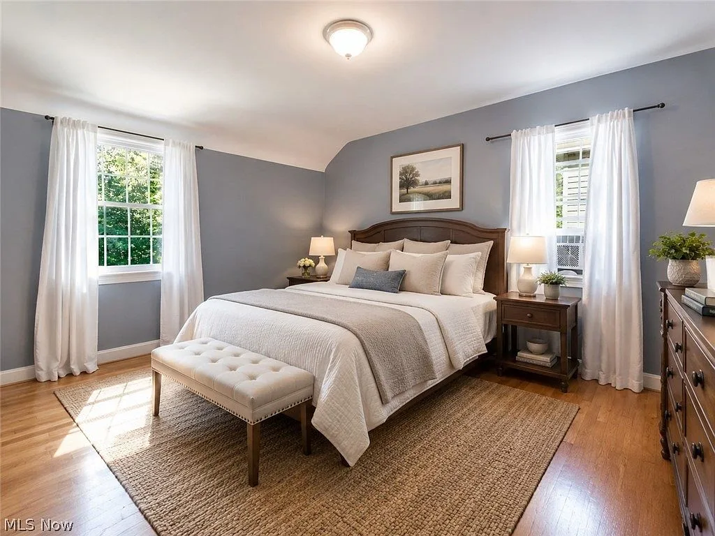 Primary bedroom with hardwood floors and light blue walls