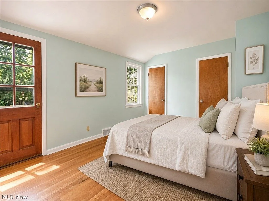 Second bedroom with hardwood floors, light blue walls, and solid wood doors