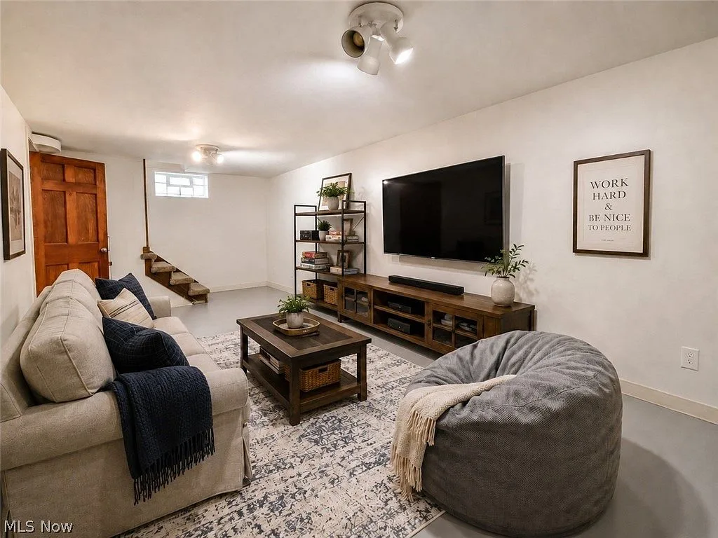 Finished basement living area with painted floors and white walls