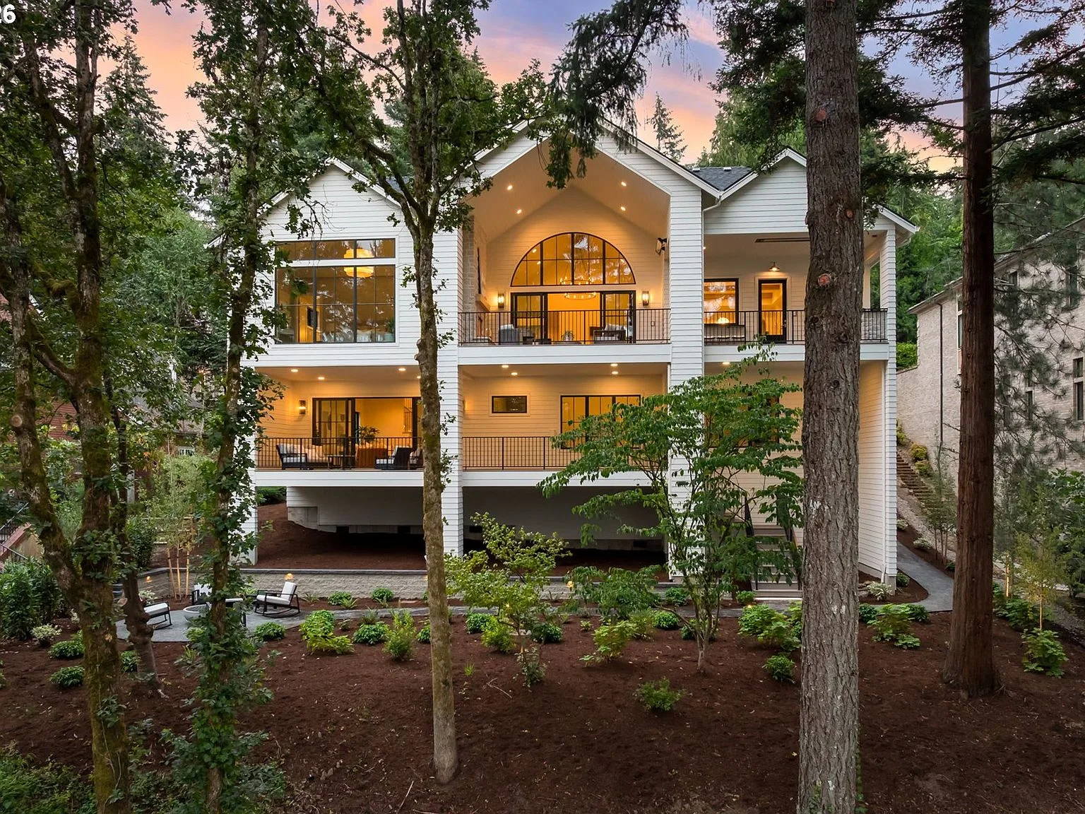 Rear facade of the residence at twilight with multi-level decks and warm interior lighting