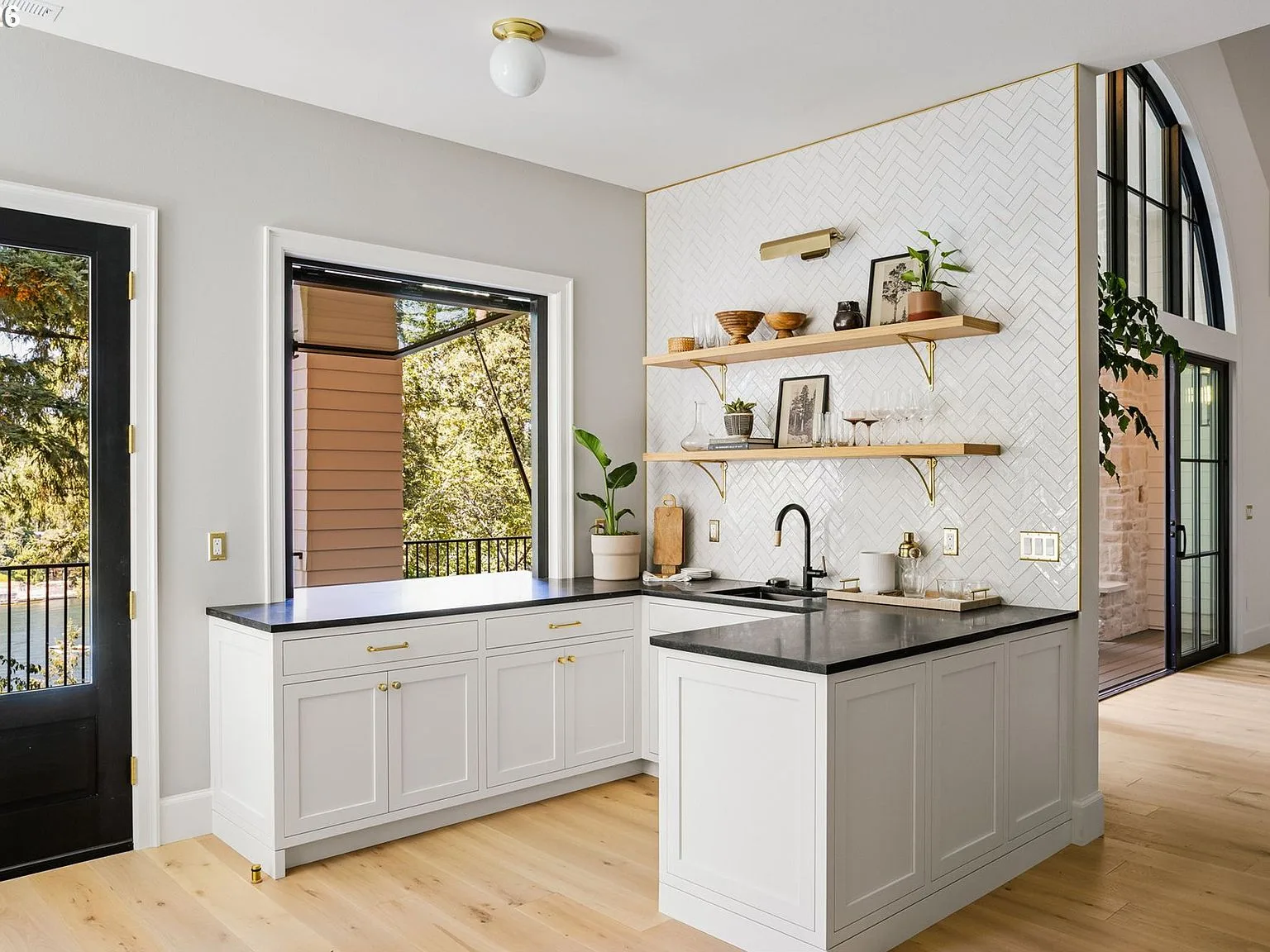 Indoor-outdoor bar area with herringbone tile backsplash and open shelving