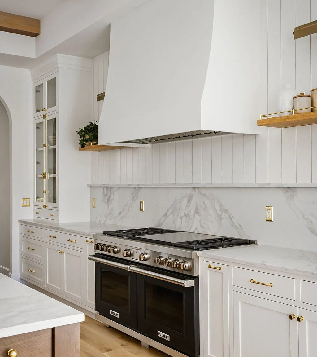 Wolf range and custom range hood with marble backsplash and brass hardware