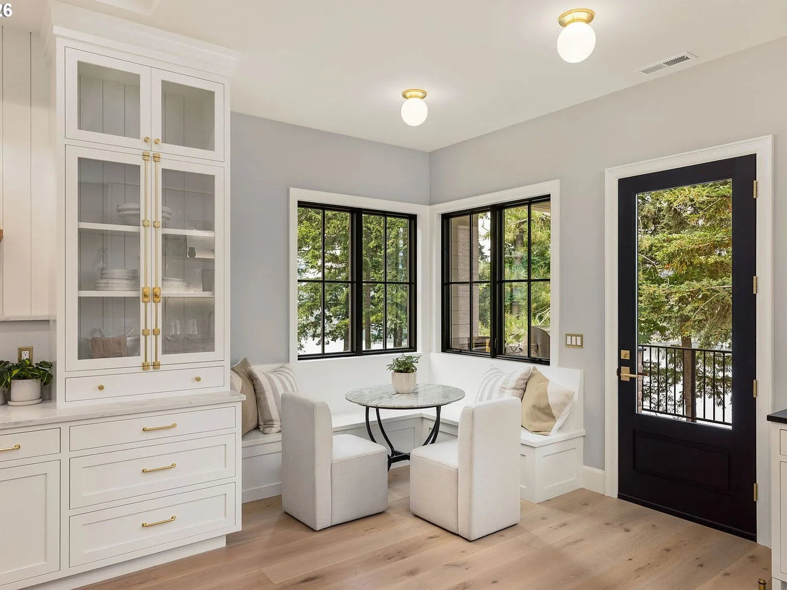 Breakfast nook with built-in bench seating, round marble table, and black window frames
