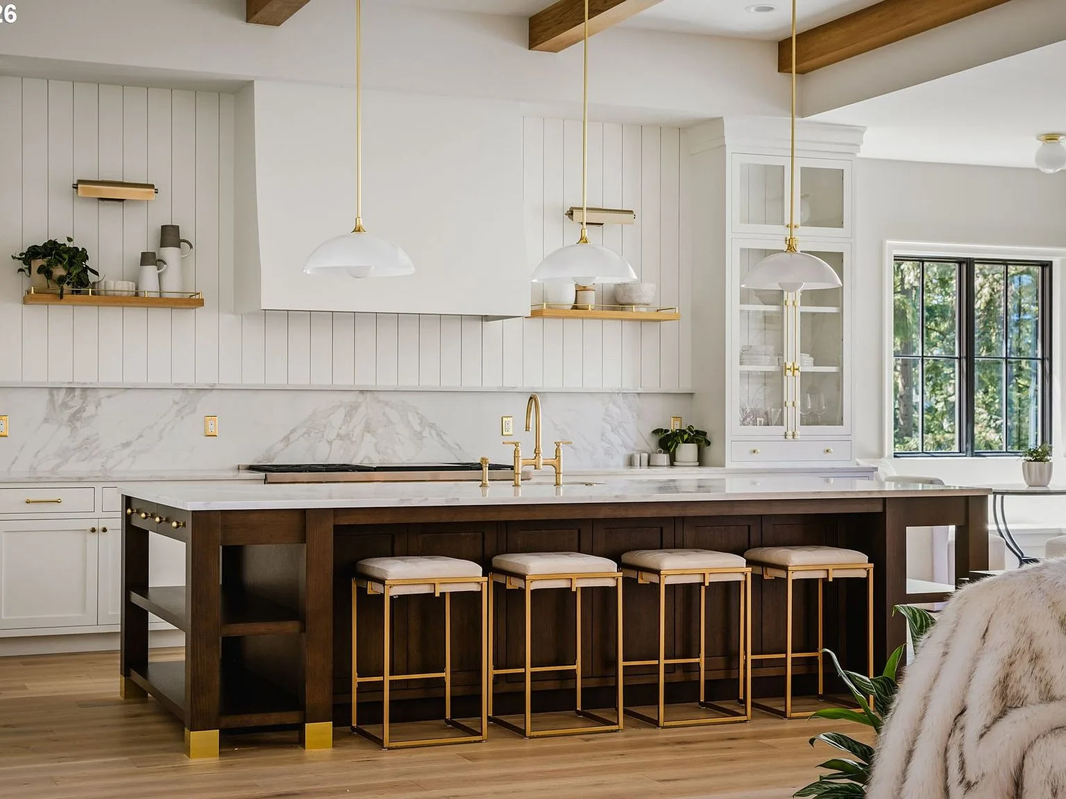 The chef's kitchen with dark stained island, marble countertops, and brass pendant lights