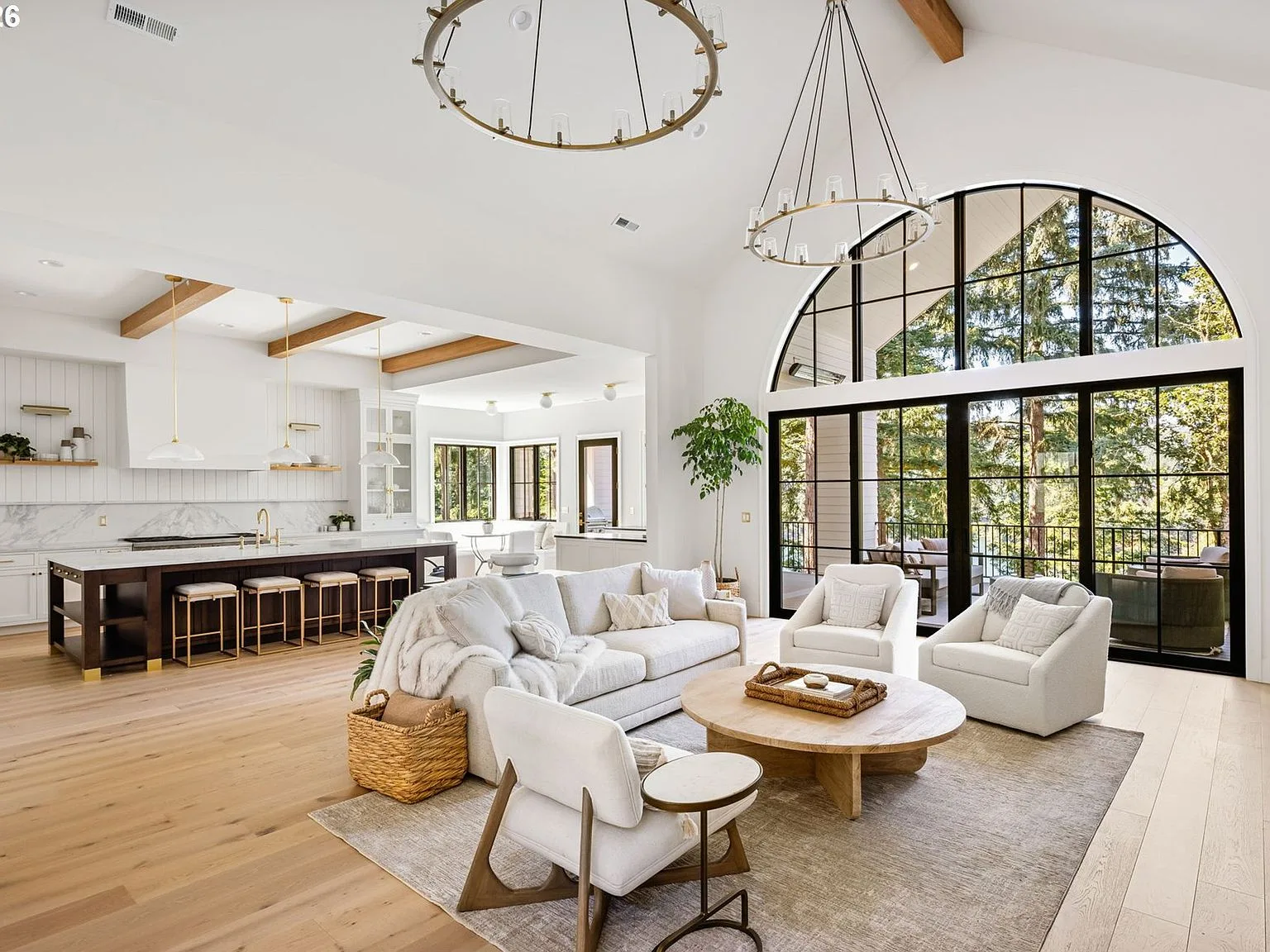 The great room with 20-foot vaulted ceilings, exposed beams, and a wall of glass opening to the terrace