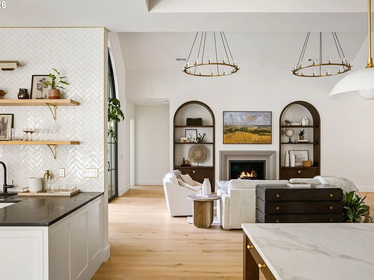 View from the kitchen into the living room with arched shelving and a fireplace