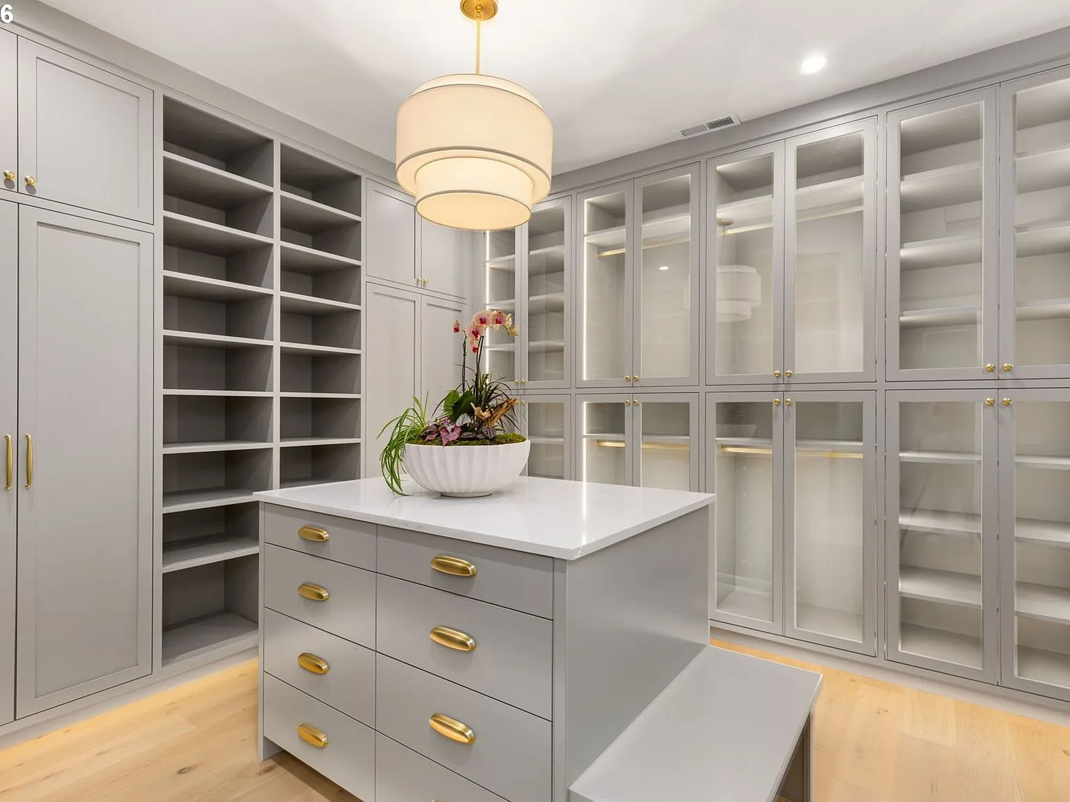Custom dressing room with glass-front cabinetry and marble-topped island