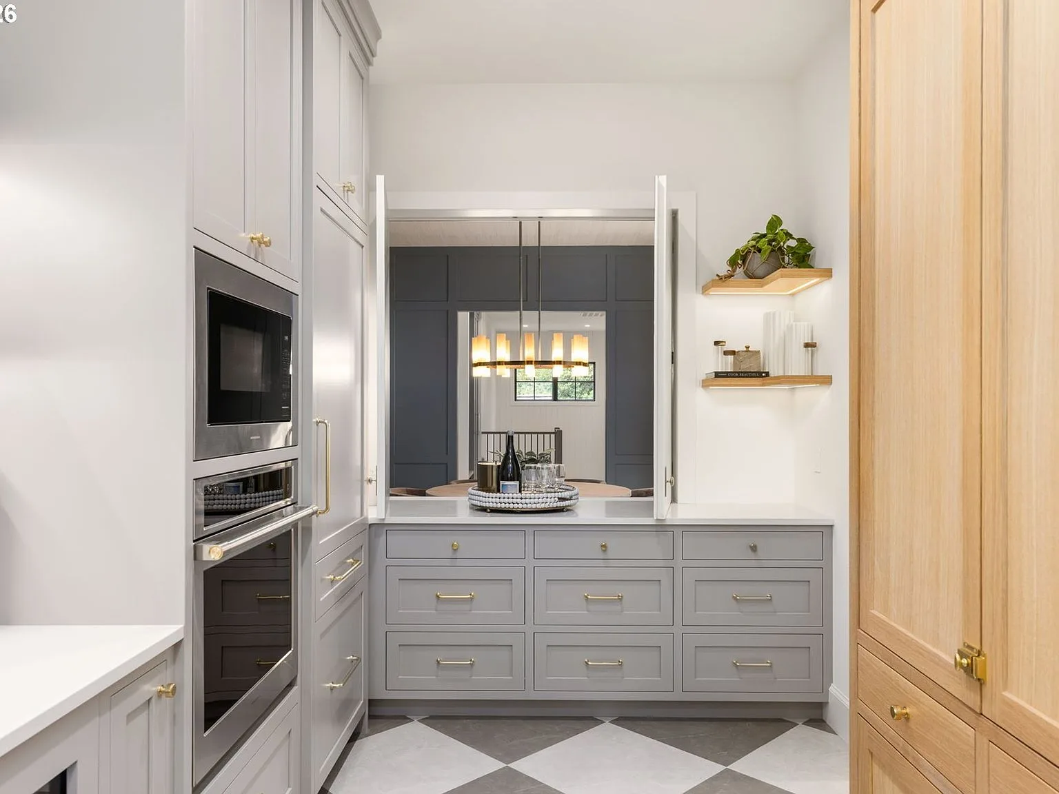 Fully equipped scullery with inset cabinetry, checkerboard tile, and wood shelving