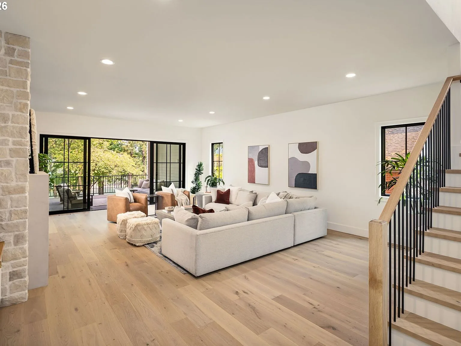 Wide-angle living room with stone fireplace wall and black-framed sliding glass doors