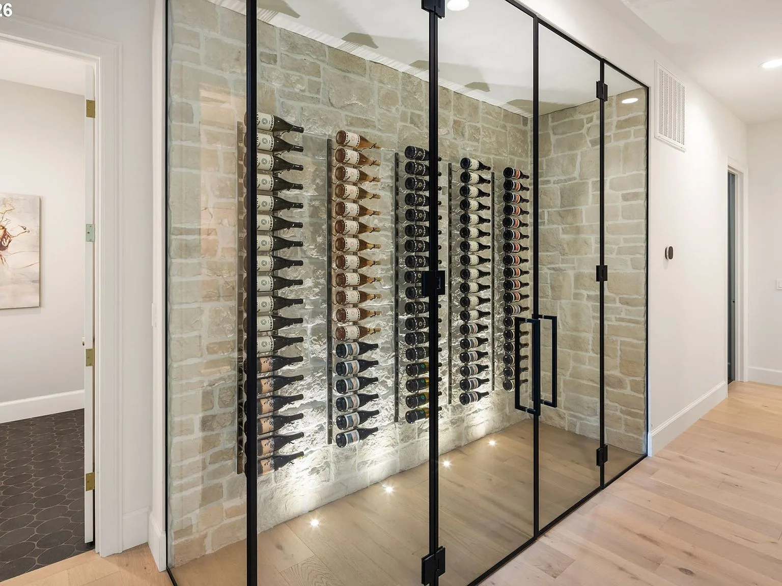 The glass-enclosed wine cellar with stone veneer and recessed floor lighting